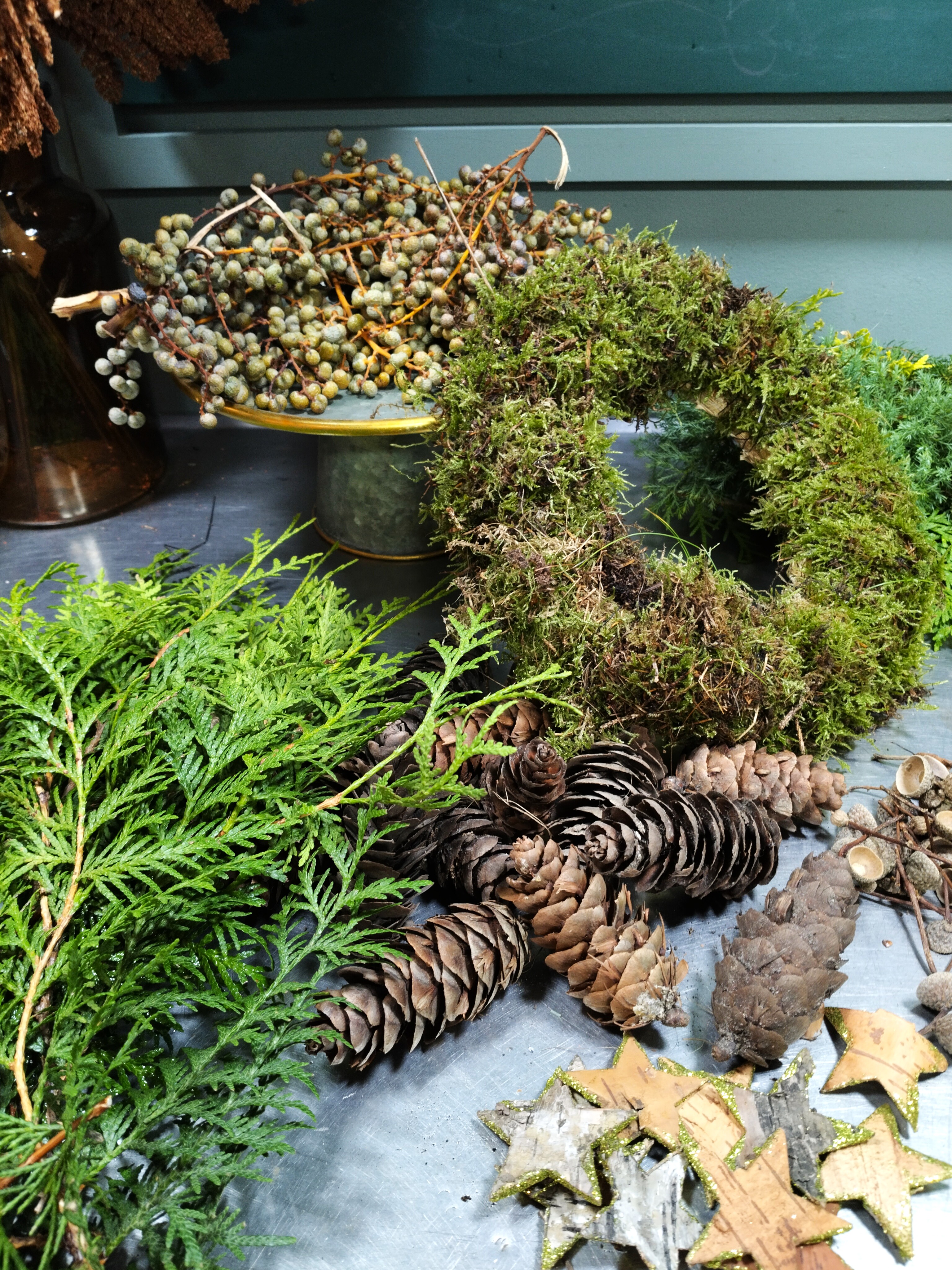 Binderbord fyldt med vintergrønt, kogler, gran og moskranse. 
