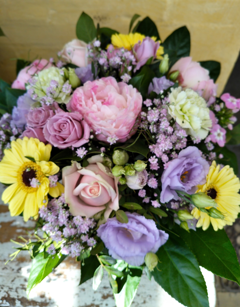 Sommerbuket med pastelfarvede blomster i gule, lyserøde og lilla nuancer. 