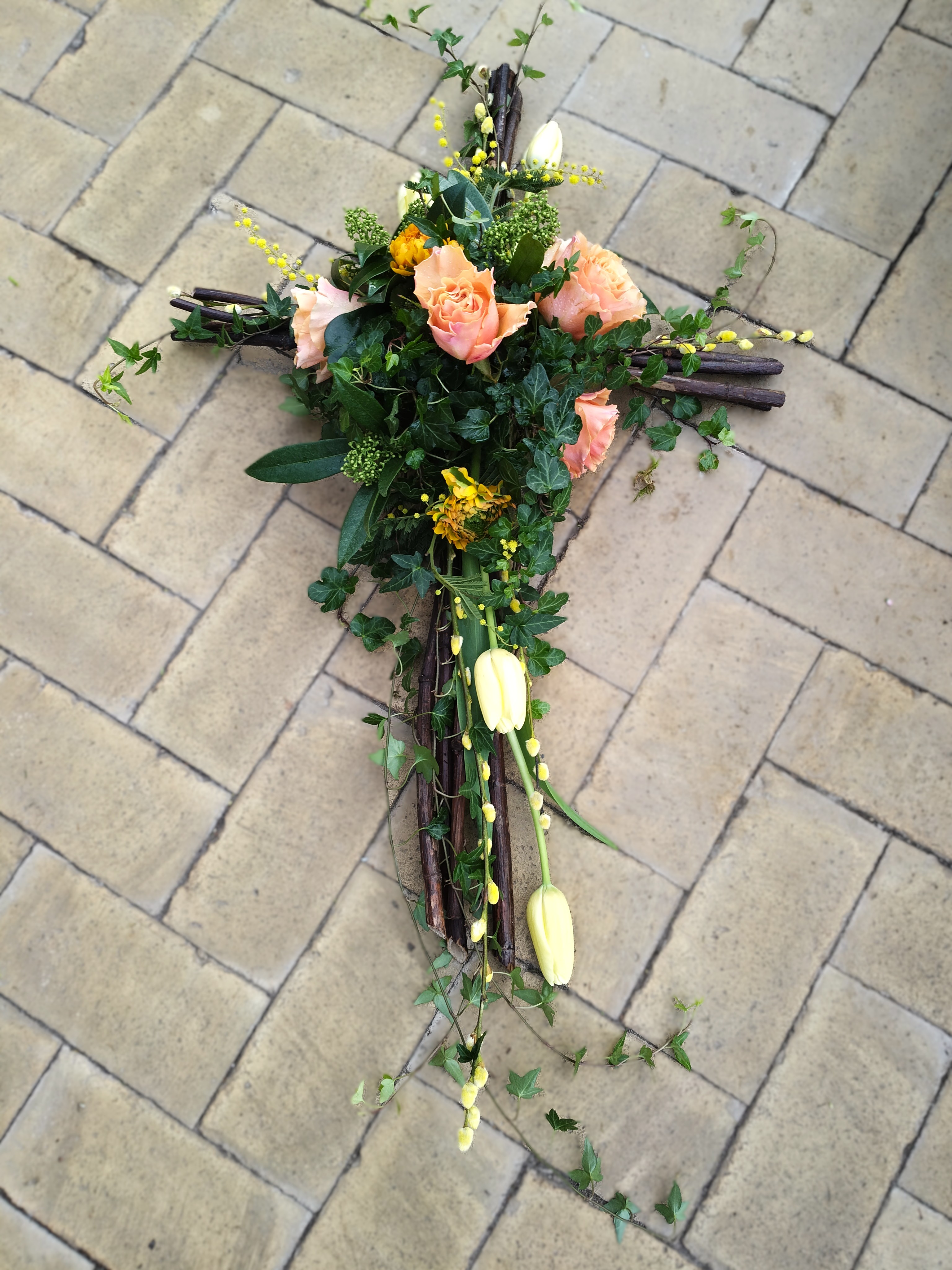 Kors lavet i grene og pyntet med efeu og roser. 