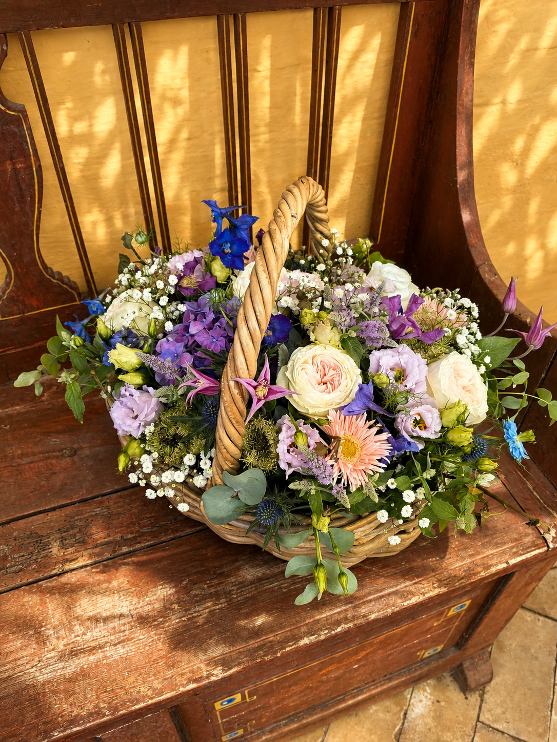 Brun fletkurv fyldt med multifarvede sommerblomster. 