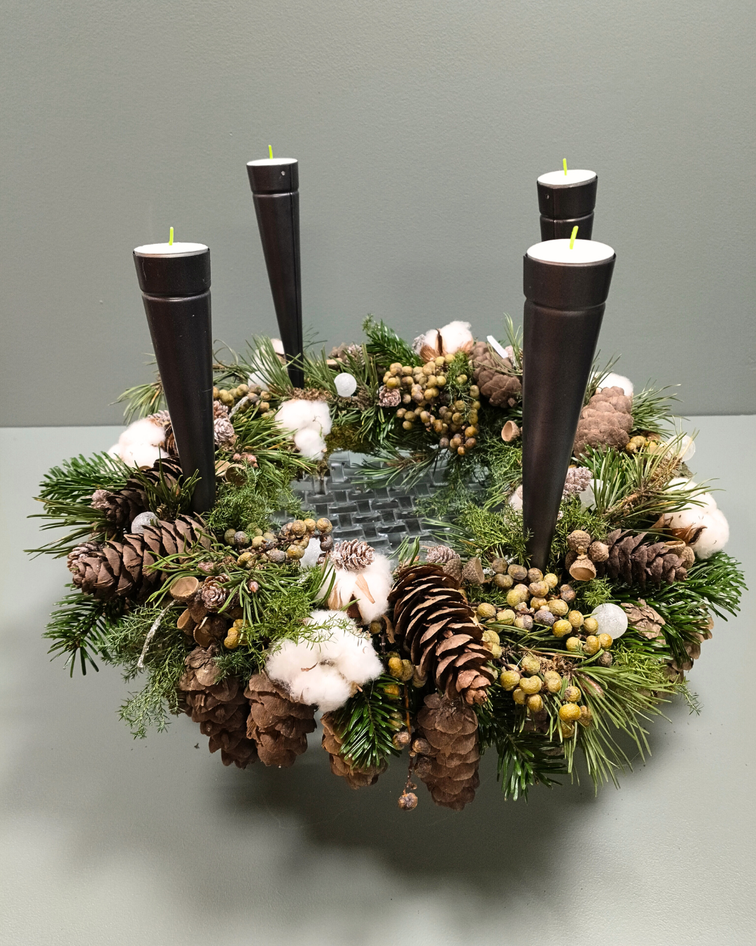 Adventskrans lavet på et fad og bundet kogler, bomuld og gran, og isat fire lyseholdere med fyrfadslys. 