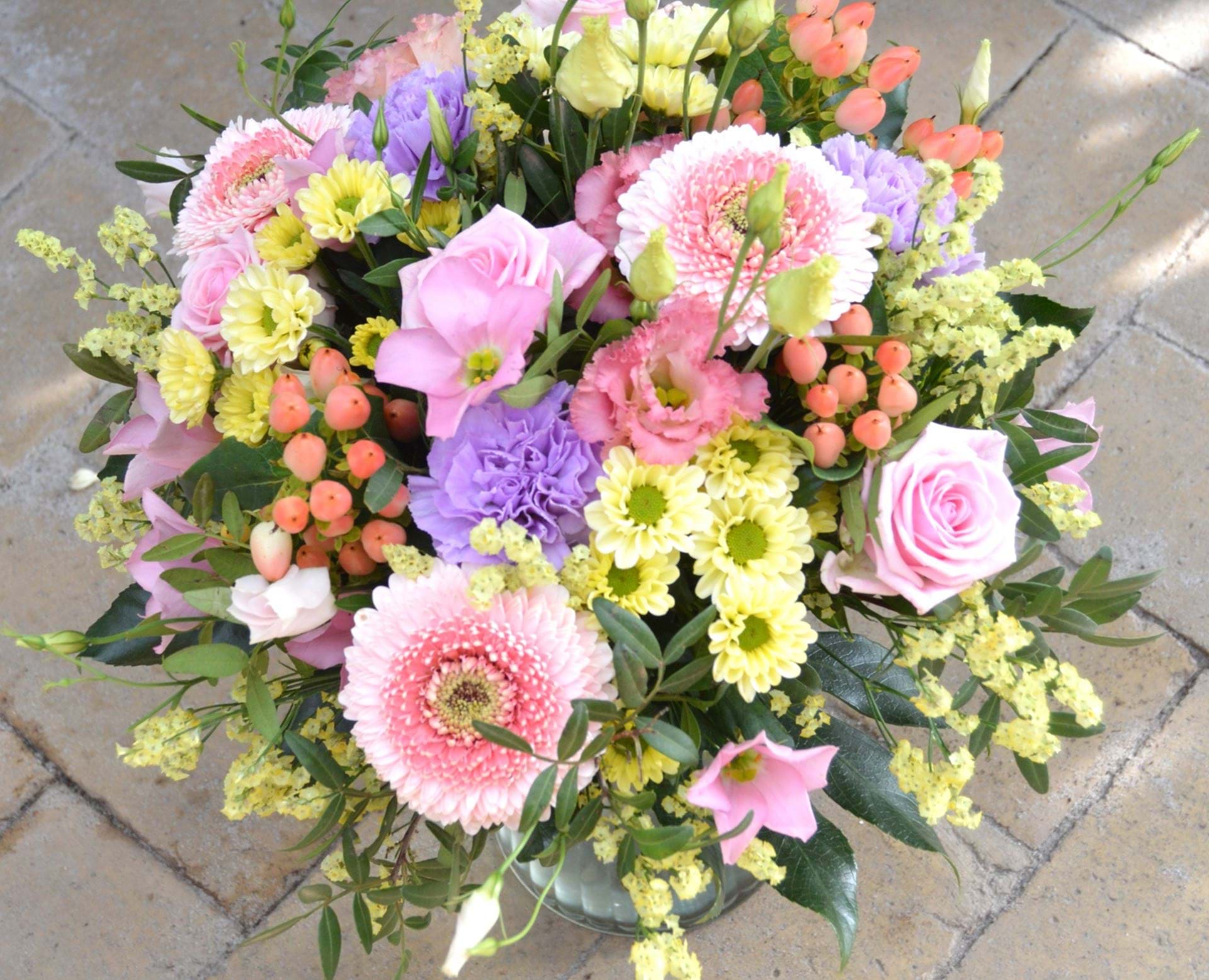 Billede af blomsterbuket i lyserøde, gule og lilla nuancer. 