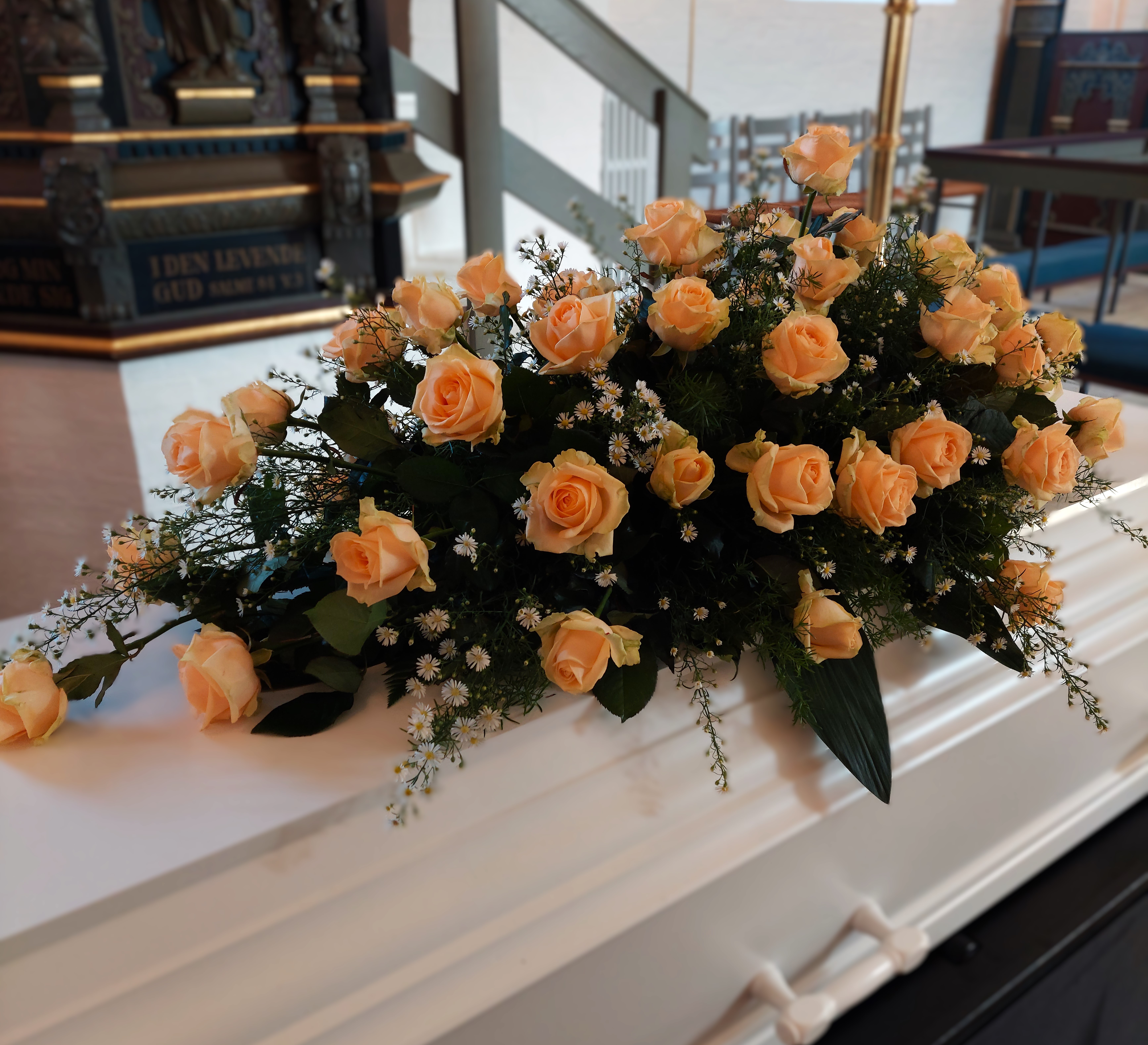 Kistepynt i orange nuancer pryder kisten med alteret i baggrunden.