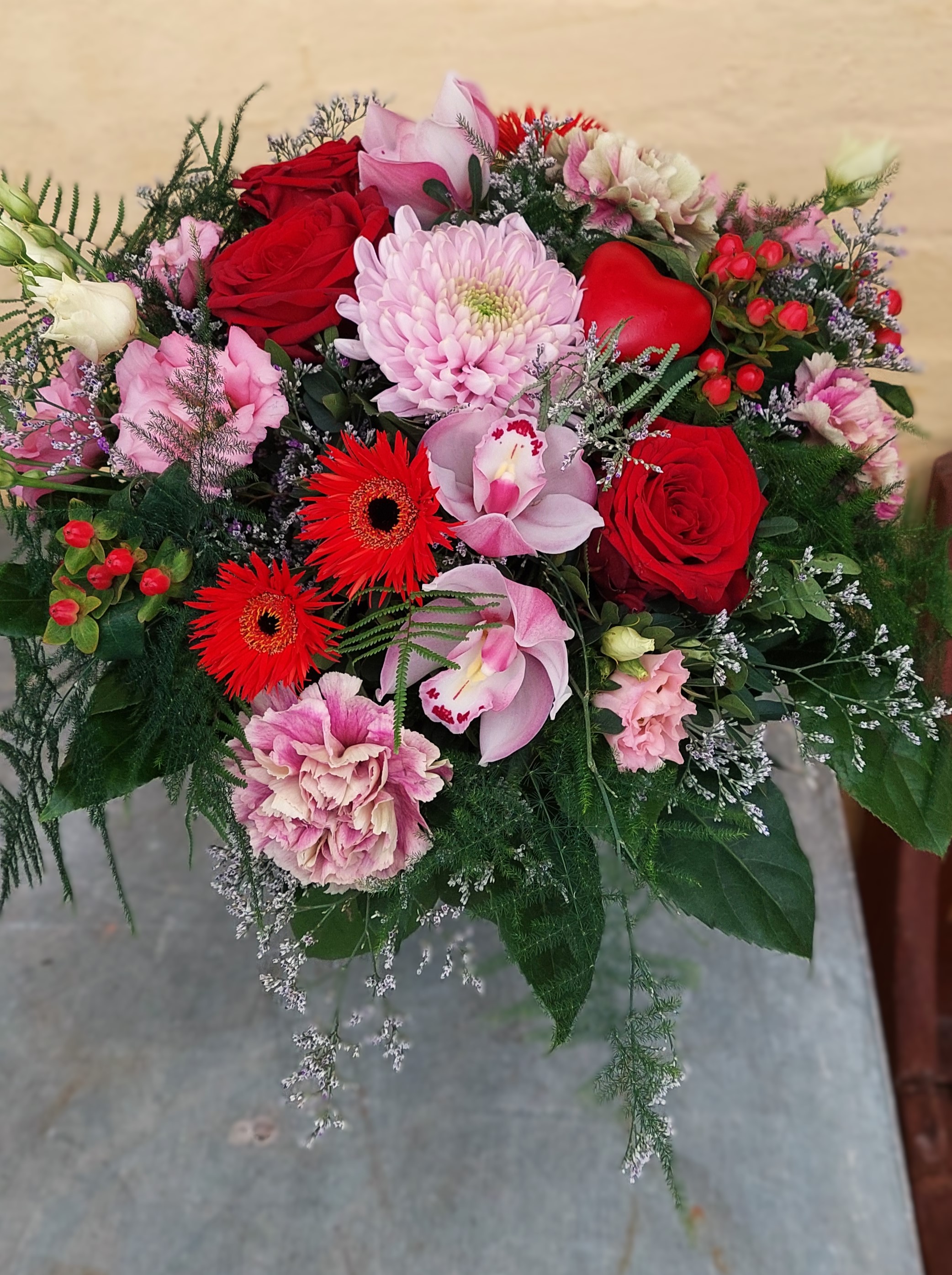 Smuk Valentinsbuket bestående af røde roser, orkideer, nellike og gerbera.