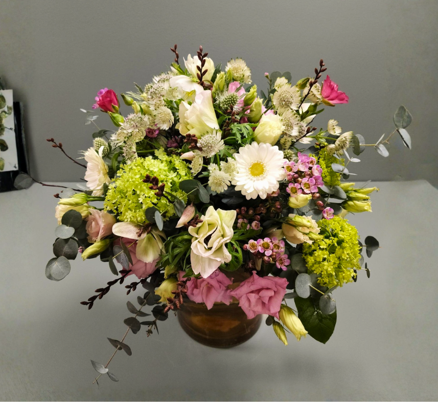 Rund og tætbundet buket i bløde pastelfarver. 